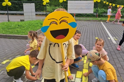 Przedszkolaki rysują kredą na placu zabaw